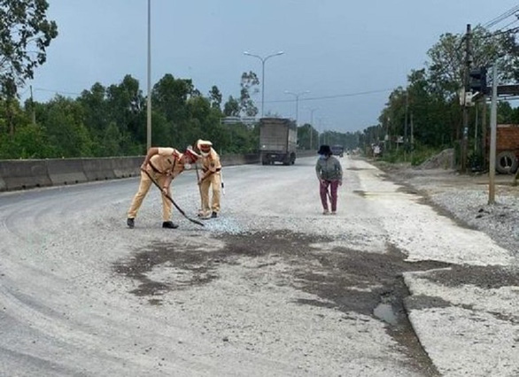 Cảnh sát giao thông dùng chổi, xẻng dọn dẹp đá dăm trên quốc lộ